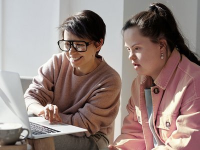 Beispielbild Zielgruppe Leichte Sprache: Zwei junge Frauen, eine mit Downsyndrom am Computer