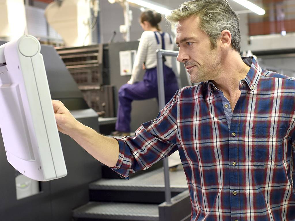 Symbolbild Mann an Druckmaschine. Anatom5 liefert bei Print alles aus einer Hand inklusive Druck.